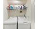 Efficient laundry room with side-by-side washer and dryer, and shelving above for storage and organization at 5710 Palmer Cir # 204, Lakewood Ranch, FL 34211