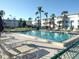 Community swimming pool surrounded by sun loungers and palm trees against a building exterior at 5889 Garden Ln # H4, Bradenton, FL 34207