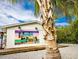 Charming island cottage with a vibrant mural on the side, nestled near a mature palm tree and lush landscaping at 6201 Holmes Blvd, Holmes Beach, FL 34217