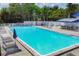 Full view of a bright community pool surrounded by lounge chairs and tables under a sunny sky at 6911 Stetson Street Cir, Sarasota, FL 34243