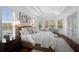 Bright bedroom featuring tray ceilings, many windows, hardwood floors, seating and an ensuite bath at 6919 Winners Cir, Lakewood Ranch, FL 34202