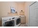 Well-lit laundry room with large washer and dryer, storage cabinets, sink, and decorated with modern art at 6919 Winners Cir, Lakewood Ranch, FL 34202
