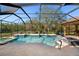 Inviting screened-in pool area with a large pool, spa, travertine tile, and lush green backyard at 6919 Winners Cir, Lakewood Ranch, FL 34202