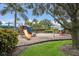 Community playground featuring a slide, swings, and playhouse surrounded by lush landscaping and trees at 8803 18Th Nw Ave, Bradenton, FL 34209