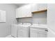 Laundry room with white cabinets, a sink, and a modern washer and dryer at 12326 Blue Hill Trl, Bradenton, FL 34211