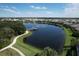 Aerial view of pond with walking path and wooden dock along the shore, surrounded by trees and landscaping at 12326 Blue Hill Trl, Bradenton, FL 34211