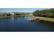 Scenic community pond view featuring a wooden dock, well maintained green spaces, and beautiful houses in the background at 12326 Blue Hill Trl, Bradenton, FL 34211
