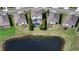 Aerial view of a home with a screened-in pool and lush landscaping, near a lake, surrounded by neighboring homes and lawns at 12716 Dusty Trail Dr, Sarasota, FL 34238