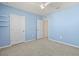 A carpeted bedroom with light blue walls is brightened by a modern ceiling fan and a large window, also features some shelving at 12716 Dusty Trail Dr, Sarasota, FL 34238