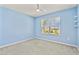 This bedroom has light blue walls and carpeted floors, also featuring a modern ceiling fan and a large window for natural light at 12716 Dusty Trail Dr, Sarasota, FL 34238