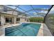 Beautiful screened in pool with blue tiling and stone decking surrounded by lush landscaping in a backyard oasis at 12716 Dusty Trail Dr, Sarasota, FL 34238