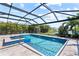 A beautiful screened-in pool and spa with blue tiling and stone decking are surrounded by lush landscaping and a tranquil lake view at 12716 Dusty Trail Dr, Sarasota, FL 34238