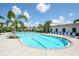Community pool featuring a large swimming area, plenty of lounge chairs, and lovely landscaping with palm trees around the perimeter at 12716 Dusty Trail Dr, Sarasota, FL 34238