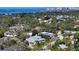 An aerial view showcases a two-story home surrounded by trees, close to the ocean, and a city skyline at 1543 Eastbrook Dr, Sarasota, FL 34231