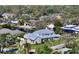 An aerial shot shows a gray two-story home with a metal roof, a lush yard, and a surrounding tree line at 1543 Eastbrook Dr, Sarasota, FL 34231