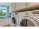 Bright laundry room with a granite countertop sink, white cabinetry, and modern washer and dryer units at 1543 Eastbrook Dr, Sarasota, FL 34231