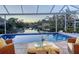 A screened in lanai with a pool overlooking a waterway with lush trees and landscaping in the background at 1543 Eastbrook Dr, Sarasota, FL 34231