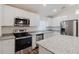 Bright kitchen featuring white cabinets, stainless steel appliances, granite counters, and a center island at 1620 Geranium Ave, North Port, FL 34288