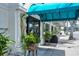 Outdoor seating area at a restaurant, featuring a blue awning, potted plants, and a sidewalk at 1631 Loma Linda St, Sarasota, FL 34239