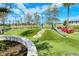 Community playground with slide, swing set, climbing area, and seating with lush, green landscape at 18771 Toulon Ct, Venice, FL 34293