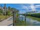 A dock extends over the calm water with a boat lift, set against a backdrop of lush greenery and a serene sky at 3491 Bayou Sound, Longboat Key, FL 34228