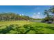 Lush green golf course with mature trees, a water feature, and golf carts on a sunny day at 3491 Bayou Sound, Longboat Key, FL 34228