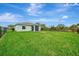 View of the home's backyard with a screened-in lanai and spacious, green lawn at 3631 Pebble Ter, Punta Gorda, FL 33980