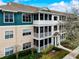 Three-story condo building with screened lanais, colorful siding, landscaping, and walkway at 4802 51 W St # 1017, Bradenton, FL 34210