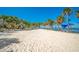 Wide sandy beach with palm trees, volleyball net and calm water, providing an active recreational space at 501 Haben Blvd # 204, Palmetto, FL 34221