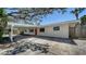 Charming single-story home featuring a covered carport, a bright red front door, and beautiful mature trees at 514 Ralph St, Sarasota, FL 34242