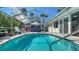 Sparkling screened-in pool with ample patio seating and a sun umbrella for relaxation at 514 Ralph St, Sarasota, FL 34242