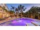 Outdoor oasis featuring a pool with evening lighting, lounge chairs, fountain and lush tropical landscaping at 601 Avenida De Mayo, Sarasota, FL 34242