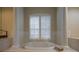 Bright bathroom with a luxurious soaking tub framed by architectural columns and a large window with shutters at 7015 Stanhope Pl, University Park, FL 34201