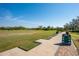 Scenic driving range view with yardage markers and mature trees against a bright blue sky at 7015 Stanhope Pl, University Park, FL 34201