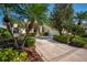 Inviting home showcasing lush landscaping, palm trees, and a driveway leading to the attached garage at 7015 Stanhope Pl, University Park, FL 34201