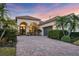 Elegant stucco home featuring a paver driveway, arched entryway, and lush tropical landscaping at 7024 Brier Creek Ct, Lakewood Ranch, FL 34202