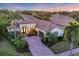 An aerial view of a Mediterranean-style home featuring a red tile roof, brick driveway, a three-car garage and lush landscaping at 7024 Brier Creek Ct, Lakewood Ranch, FL 34202