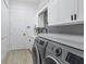 Bright laundry room with white cabinets, modern washer/dryer, and stylish black hardware at 7024 Brier Creek Ct, Lakewood Ranch, FL 34202