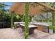 Beautiful outdoor kitchen with stone accents, bar seating, pergola, and lush greenery in a relaxing backyard setting at 7024 Brier Creek Ct, Lakewood Ranch, FL 34202