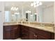 Bathroom with granite countertops, dark wood cabinets, and dual sinks with large mirrors and modern lighting at 8043 St Simons St, Bradenton, FL 34201