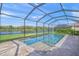 Screened-in pool area with a spa, overlooking lush landscaping and a tranquil lake view at 8294 Barton Farms Blvd, Sarasota, FL 34240