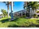 Backyard view of screened in lanai with pool, landscaping, and tropical palm trees at 9332 Miami Cir, Port Charlotte, FL 33981