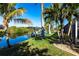 Waterfront home featuring a private dock with boat lift and lush tropical landscaping at 9332 Miami Cir, Port Charlotte, FL 33981