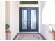 Elegant double front doors with decorative glass, flanked by colorful planters, create a welcoming entrance at 9332 Miami Cir, Port Charlotte, FL 33981