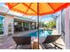 Relaxing pool area featuring lounge chairs, umbrella, and view of the screen enclosed pool at 9332 Miami Cir, Port Charlotte, FL 33981
