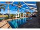 Beautiful pool area with screened enclosure, palm trees, and waterfront views at 9332 Miami Cir, Port Charlotte, FL 33981