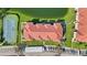 Drone image of condo building with red tile roof and a tennis court, parking and lake at 1005 Villagio Cir # 106, Sarasota, FL 34237