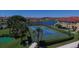 Aerial view of a blue tennis court in a residential community by a lake and multiple buildings at 1005 Villagio Cir # 106, Sarasota, FL 34237