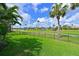 Lush green backyard featuring a black fence, palm trees, and a serene golf course view at 10509 Winding Stream Way, Bradenton, FL 34212