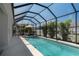 Screened in pool with lounge seating, an umbrella and lush landscaping at 10914 Blue Magnolia Ln, Parrish, FL 34219